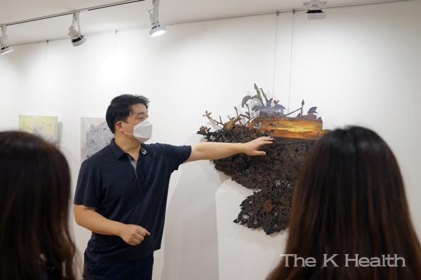 김민수 작가가 유디갤러리를 찾은 관객에게 작품을 설명하고 있다.(사진제공 : 유디치과)